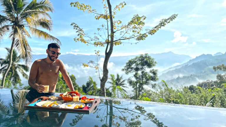 Guest enjoying a floating breakfast at Aarunya’s pool with a scenic view