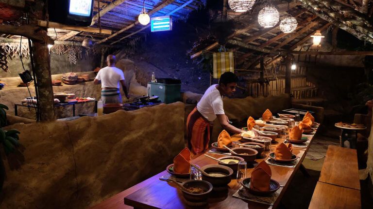 Waiter setting a traditional Sri Lankan dinner spread at Aarunya