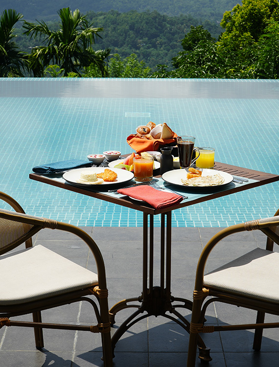 Poolside dining setup for two with a delicious spread at Aarunya Nature Resort