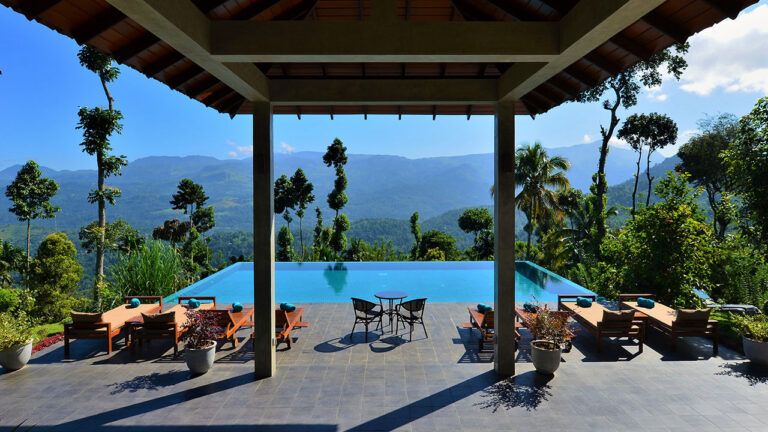 Outdoor infinity pool with sun loungers and breathtaking nature views at Aarunya