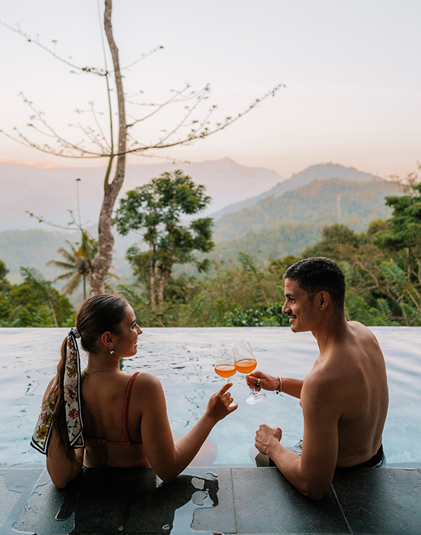 Couple toasting in the pool with a stunning view at Aarunya Nature Resort