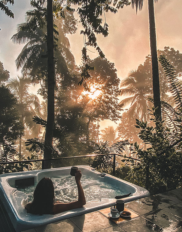 Guest relaxing in an outdoor jacuzzi with a sunset and nature views at Aarunya Nature Resort
