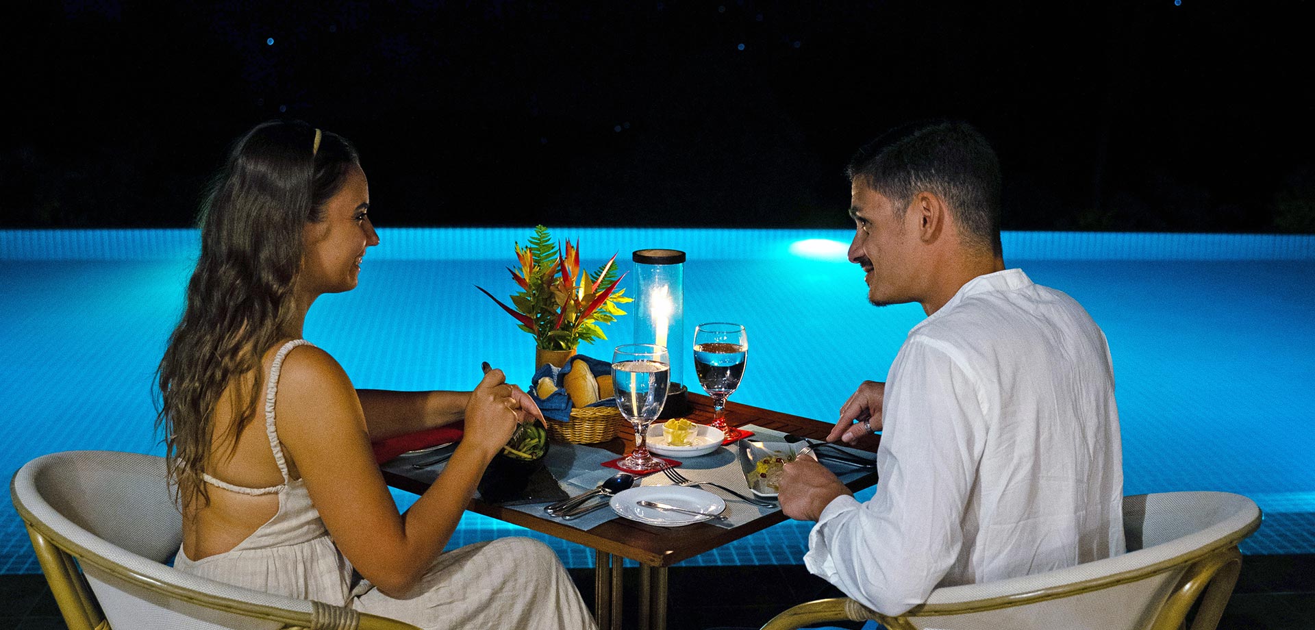 Couple enjoying a romantic poolside dinner at Aarunya Resort