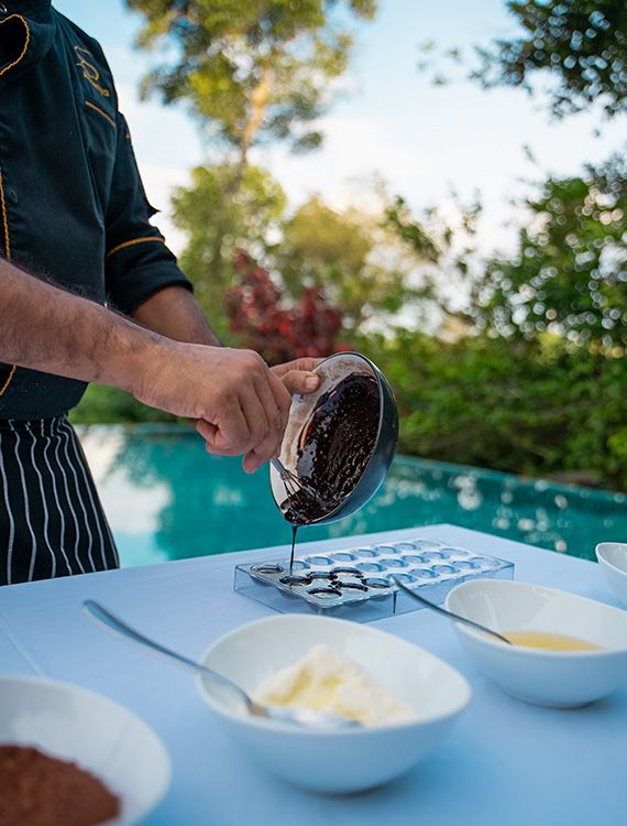 Chef at Aarunya Nature Resort pouring chocolate mixture into a cube tray