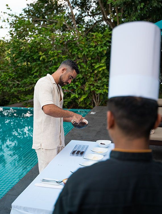 Guest making chocolate with a chef by the pool at Aarunya Nature Resort