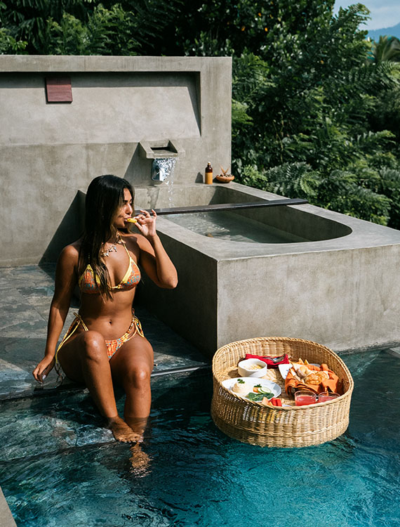 Guest enjoying a floating breakfast at Aarunya’s pool with a scenic view