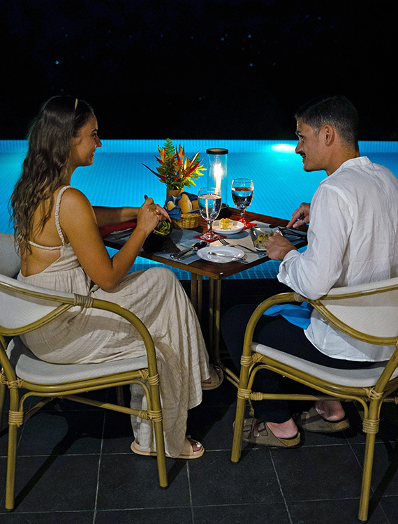 Couple enjoying a romantic poolside dinner at Aarunya Resort