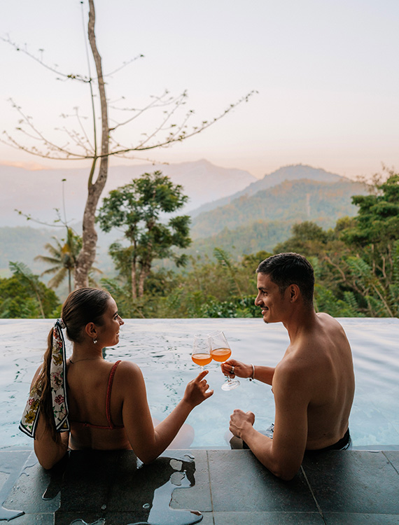 Couple toasting in the pool with a stunning view at Aarunya Nature Resort