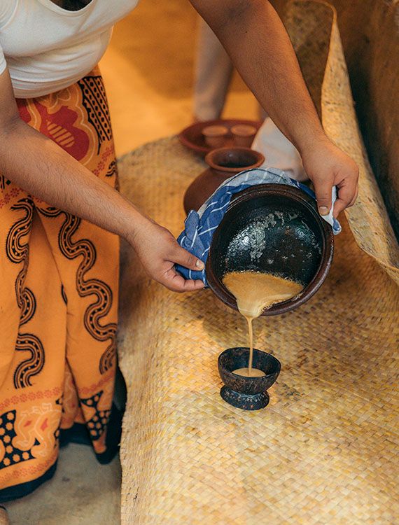 Pouring kithul treacle into  a coconut shell cup at Aarunya Nature Resort