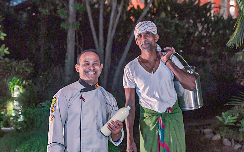 Chef and local supplier smiling as the chef holds fresh milk at Aarunya Nature Resort
