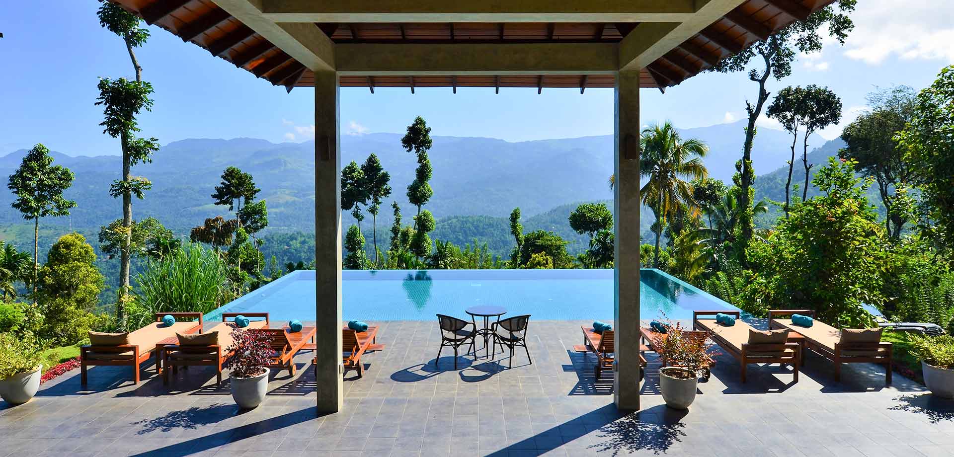 Outdoor infinity pool with sun loungers and breathtaking nature views at Aarunya