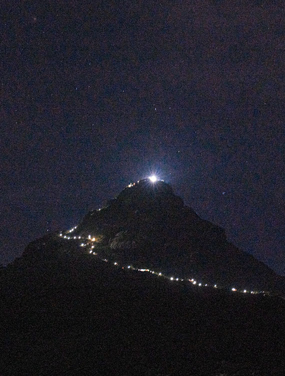Night view of Adam’s Peak with a trail of lights