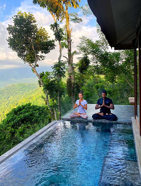 Couple practicing yoga by the pool at Aarunya Nature Resort Villa